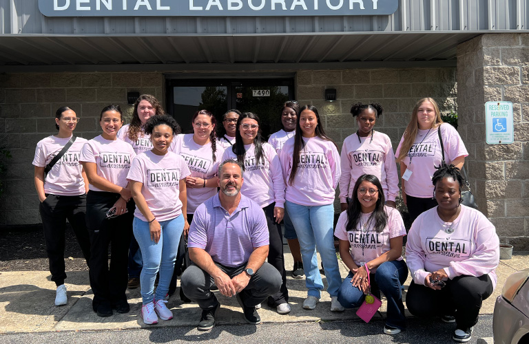 TCAT dental students standing with Daxton in front of the R-Dent Lab building