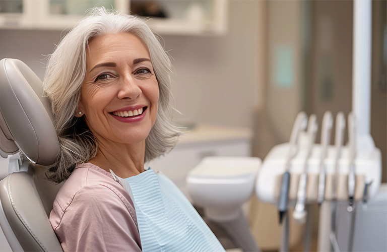 Patient sitting in a dental chair and smiling at the camera