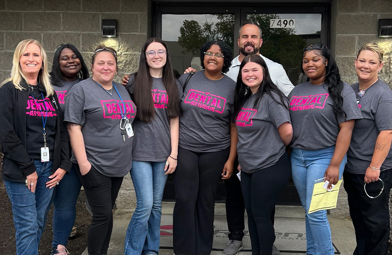 TCAT dental students standing with Daxton in front of the R-Dent Lab building