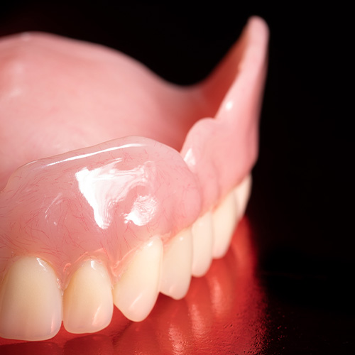 R-Dent denture on red reflective background