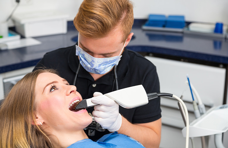 Dentist scanning a patient's mouth in a dental office.